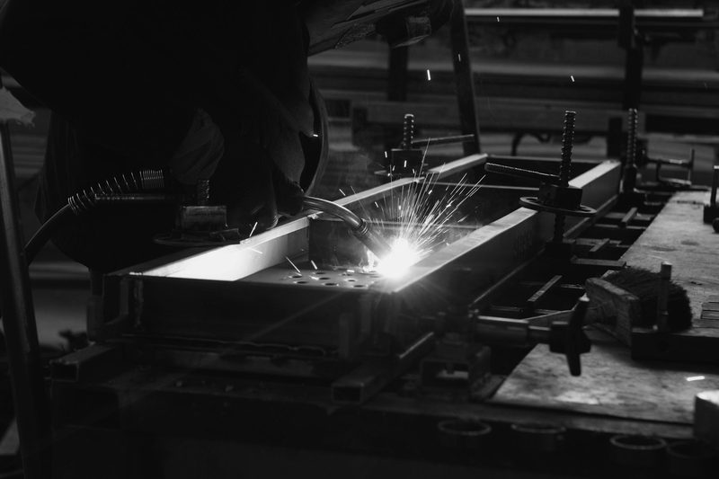 A welder working on a metal component in a fabrication workshop